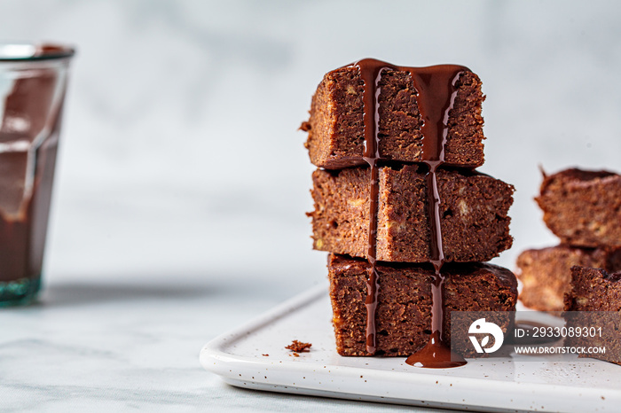 Stack of vegan brownies with dark chocolate on white board, white background. Vegan dessert concept.