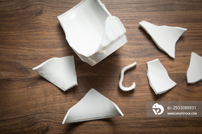 White broken cup on the wooden background.