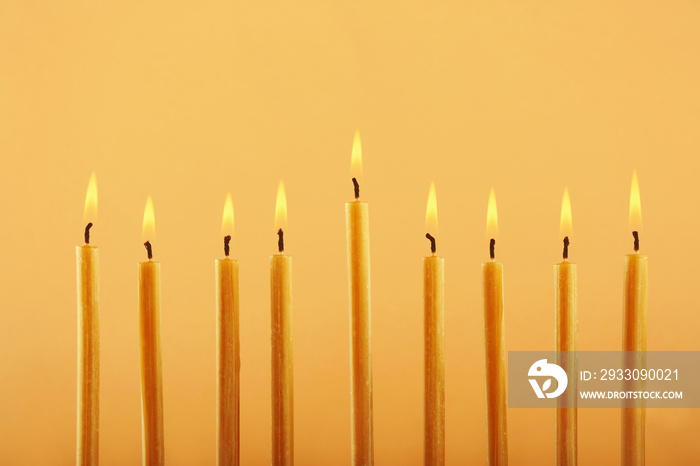 Nine burning candles on color background. Hanukkah concept