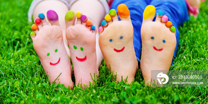 Children’s feet with a pattern of paints smile on the green grass. Selective focus.