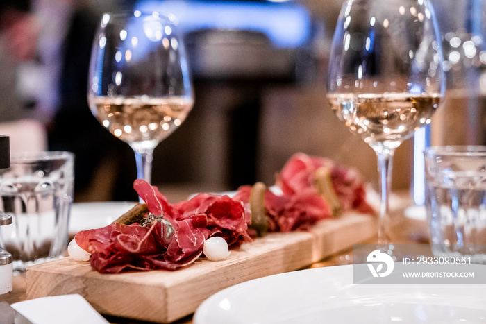 Close-up of food served on wooden plate. Wineglasses arranged by food on dining table. Delicious meal at eating place in luxurious ski resort.