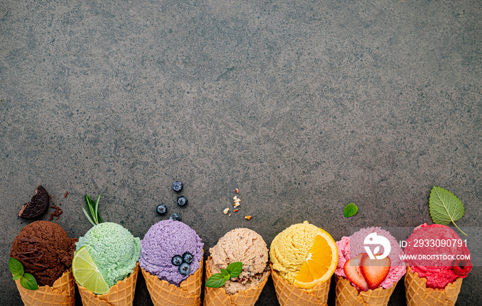 Various of ice cream flavor in cones blueberry ,lime ,pistachio ,almond ,orange ,chocolate ,vanilla and coffee set up on dark stone background . Summer and Sweet menu concept.