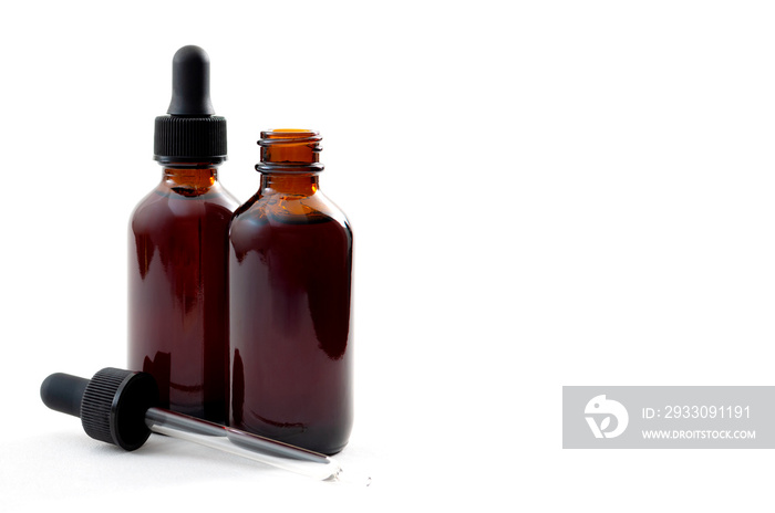 Homeopathic remedy and liquid tincture medicines concept with close up on two brown medicine glass bottles, one open and one closed with dropper isolated on white background with copy space