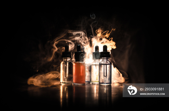 Vape concept. Smoke clouds and vape liquid bottles on dark background. Light effects. Useful as background or vape advertisement or vape background. Selective focus