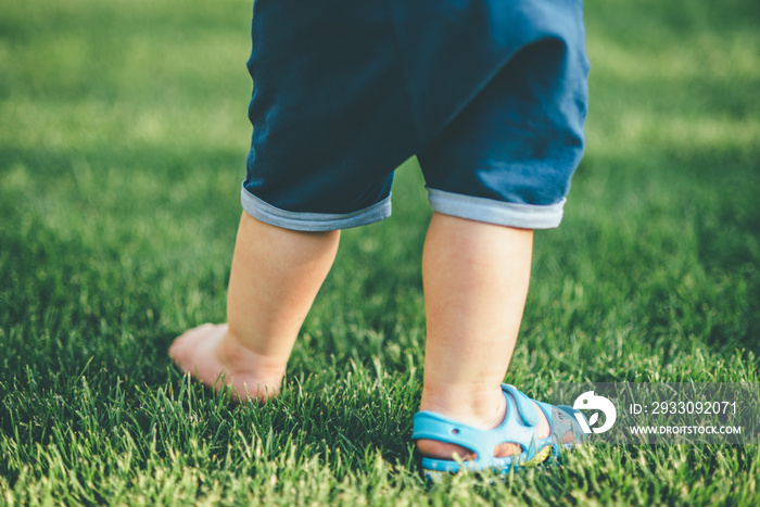 small kid is walking on the grass in shoes