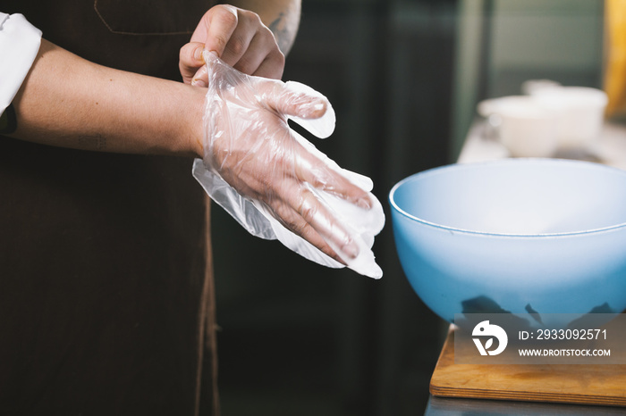 The chef wears gloves to mix the salad in the kitchen