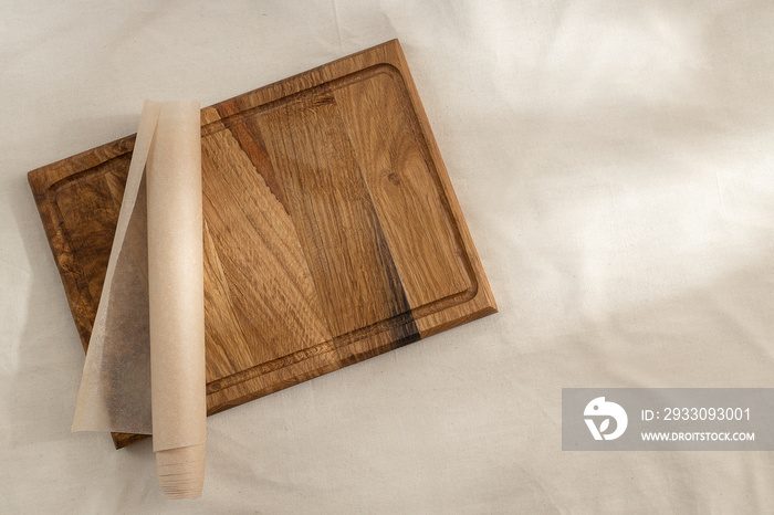 Top view of wooden cutting board,baking paper on the empty tablecloth.Free space