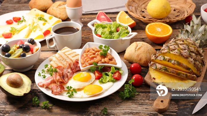 english full breakfast with fried egg, bacon,cheese, toast, coffee and fruits