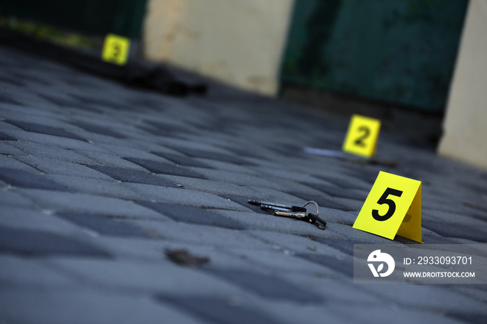 Evidence with yellow CSI marker for evidence numbering on the residental backyard in evening. Crime scene investigation concept