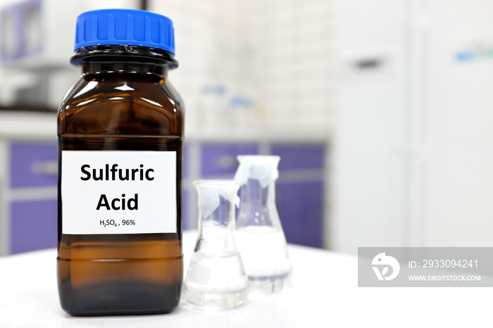 Selective focus of strong sulfuric acid chemical in brown amber glass bottle inside a laboratory with copy space.