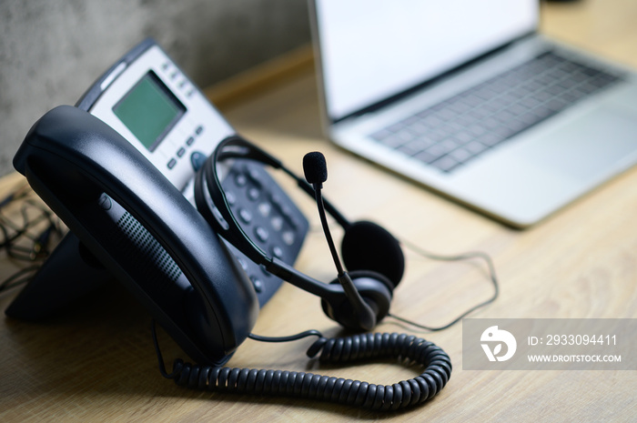 IP telephone with headset and laptop computer on wood table, office work space