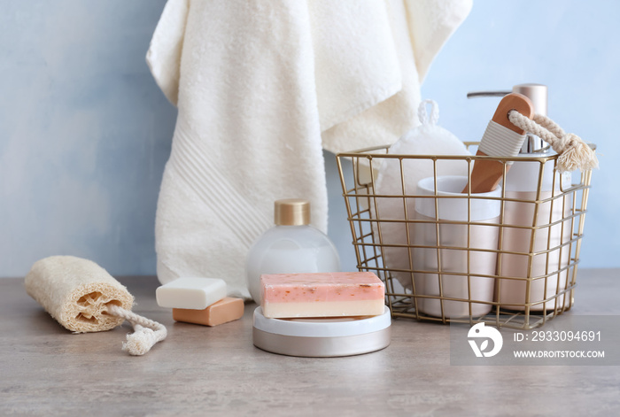 Metal basket with bath accessories and soap on table in bathroom