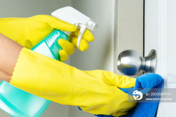 Cleaning door knob with alcohol spray for Covid-19 Coronavirus prevention