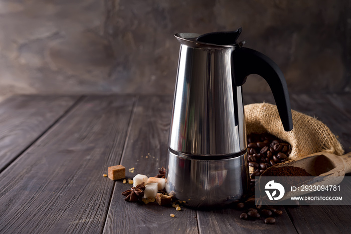 geyser coffee maker on the background of a bag of coffee and sugar grains on a dark wooden background, copy space