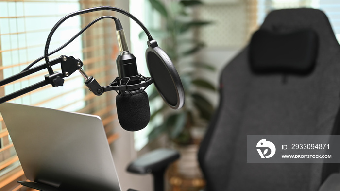 A professional condenser microphone, laptop computer in home studio interior. Entertainment, podcasts and technology concept