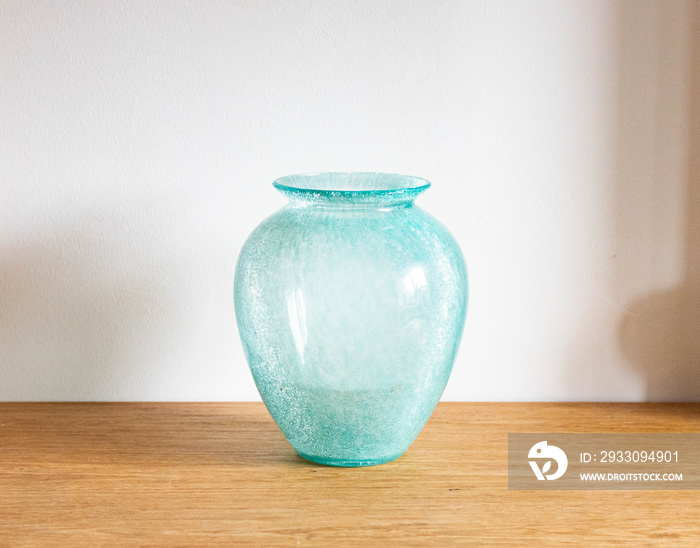 Mid-century modern turquoise blue glass vase - on a wooden table  with white background