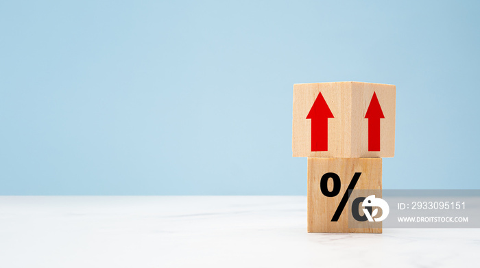 Wooden cubes with red arrows up and percent symbols on marble with a light blue background