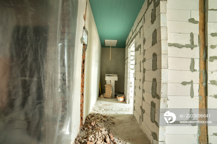 Interior of an apartment room with bare walls and ceiling under construction.