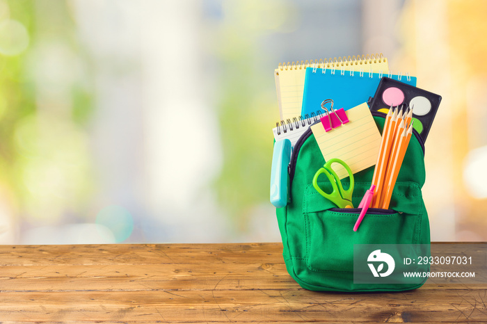 Back to school concept with bag backpack and school supplies on wooden table over abstract background