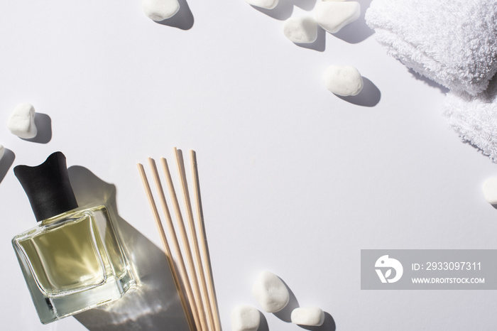 top view of aroma sticks with perfume in bottle near spa stones and towel on white background