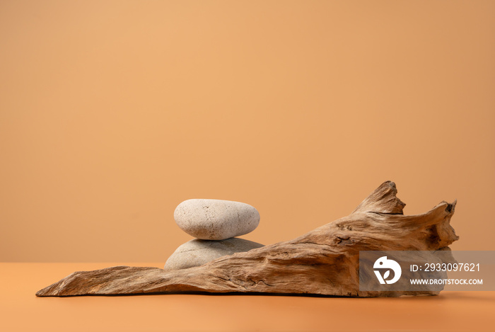 Mockup stage for advertising made with stones and weathered snag on a sandy background with copy space. Natural pedestal for cosmetic product presentation or package advertisement.