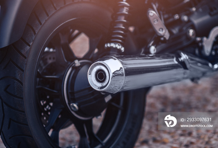 Close-up motorcycle exhaust pipe with classic wheel