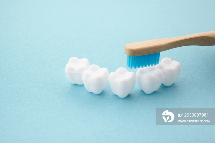 child’s hand with toothbrush and white platic tooth on blue background