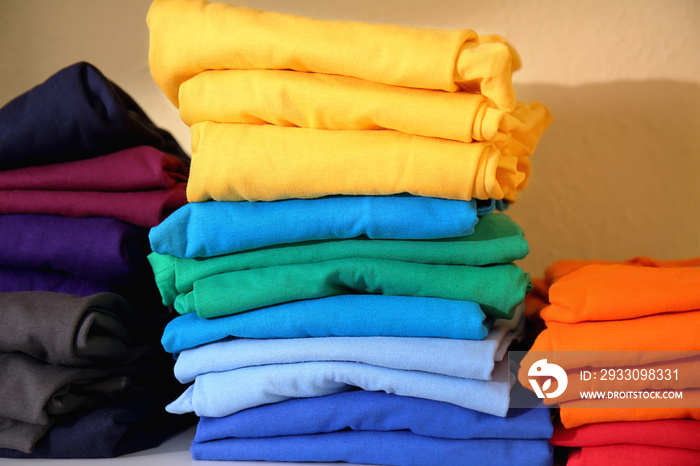 Stacks of colorful t-shirts prepared for printing on shelf