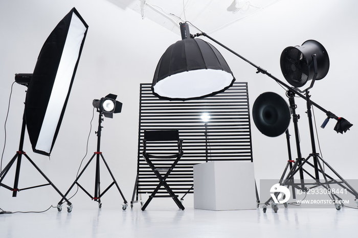 Crystal White room cyclorama. Modern photo studio with professional equipment. Empty photo studio with lighting equipment. Interior of modern photo studio with director production chair.