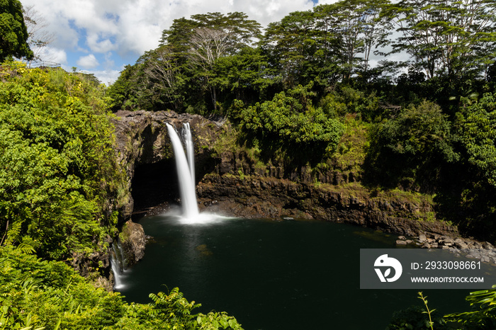 A beautiful long exposure of a waterfall on a tropical island surrounded by lush green vegetation.