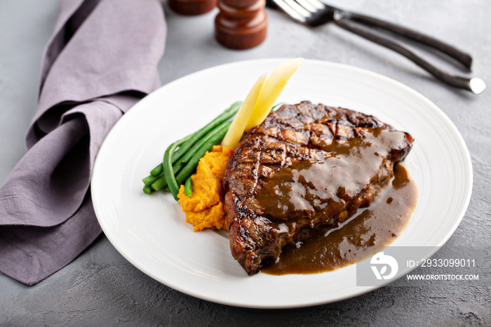 Grilled beef steak with gravy and vegetables