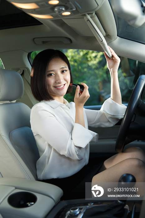 青年女人在汽车里化妆