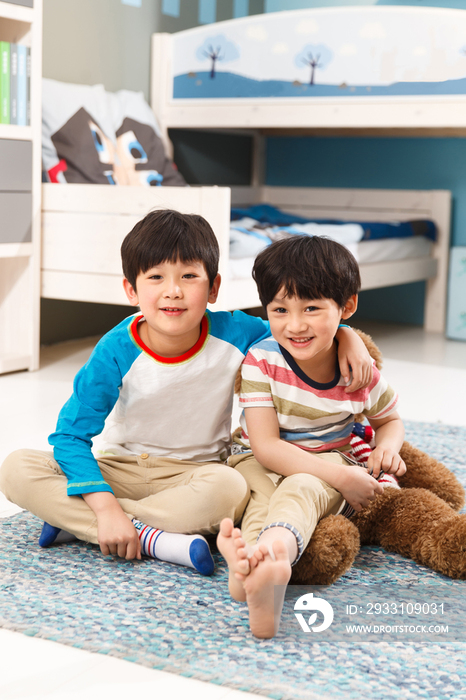 两个男孩坐在卧室的地毯上