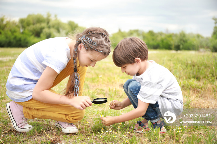 Little children with magnifying glass studying nature outdoors