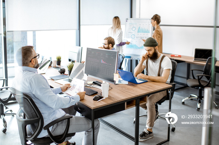 Group of diverse colleagues working on the computers in the modern office or coworking space, writin