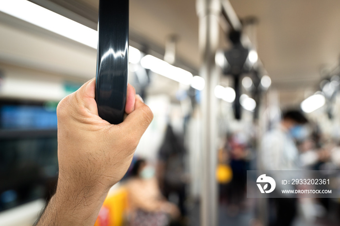 Close-up at passengers hand that holding on the railing hook in public train or metro. With blurred