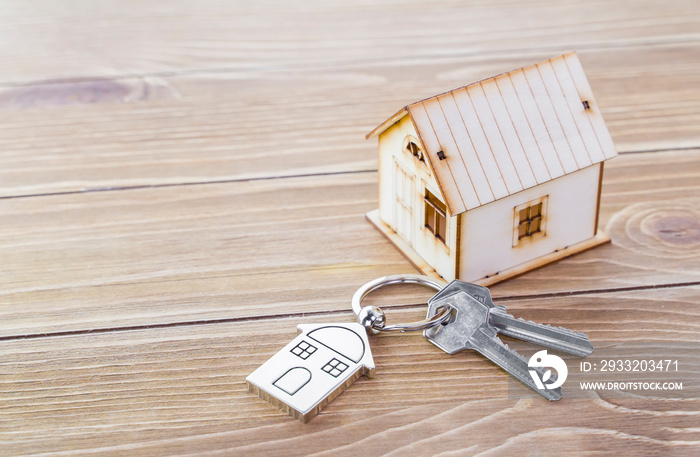 钥匙链，带有房屋符号和木背景钥匙，房地产概念
