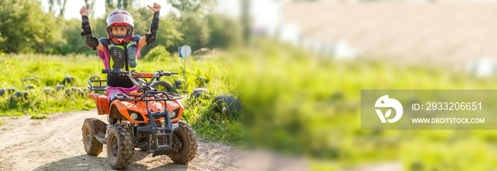 The little girl rides a quad bike. A mini quad bike is a cool girl in a helmet and protective clothi