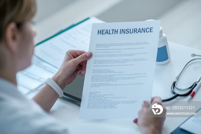 Woman in a lab coat reading a health insurance agreement