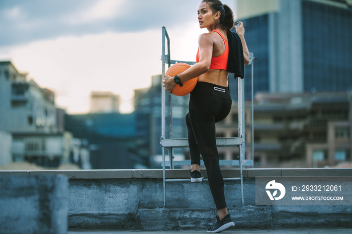 Female athlete standing on rooftop staircase looking away