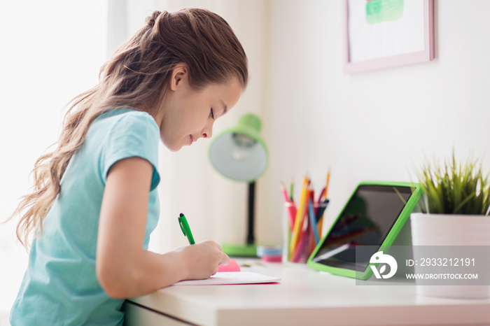 girl with tablet pc writing to notebook at home