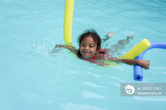 Multi racial Fijian girl child learning to swim with coloured floats