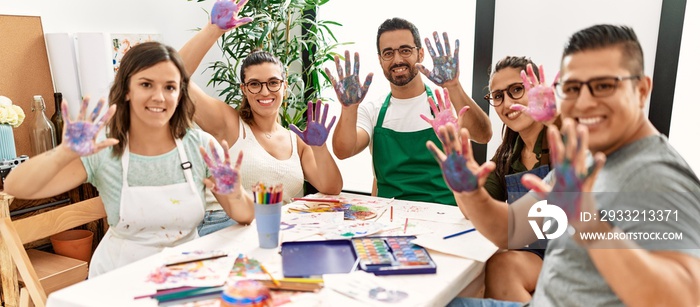 一群绘画学生坐在艺术工作室的桌子上，展示画好的手掌。