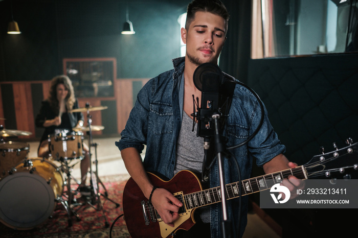 Music band having rehearsal in a studio