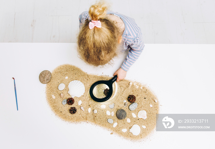 Young blonde girl child learning in montessori style class room or home concept. Explores natural na