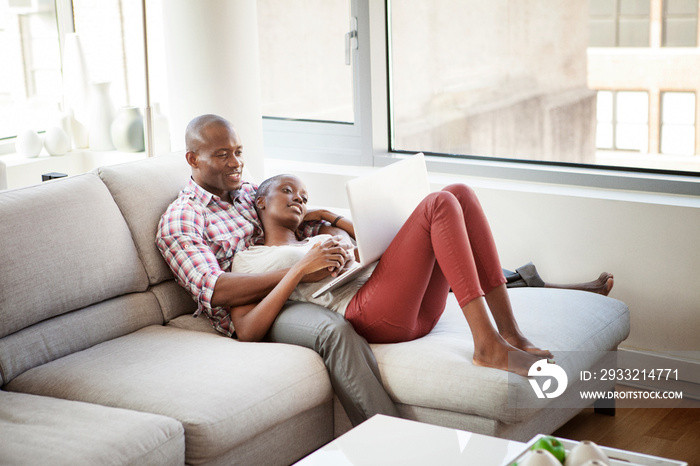 Couple using laptop on sofa at home