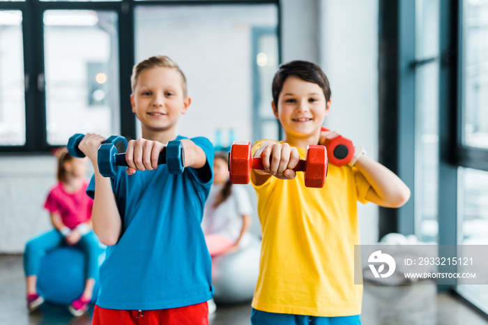 Excited boys doing exercise with dumbbells together