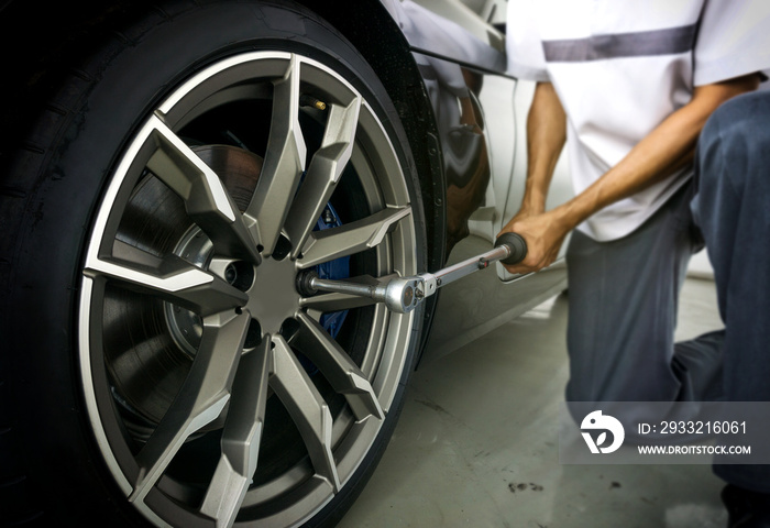 汽车修理工使用扭矩扳手检查车轮螺母，以确保行驶安全