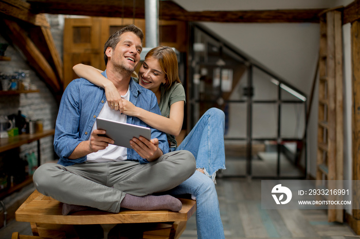 Young couple is using a digital tablet and smiling in kitchen at home