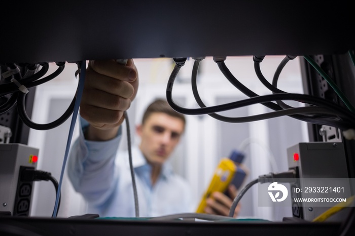 Technician using cable tester while fixing server